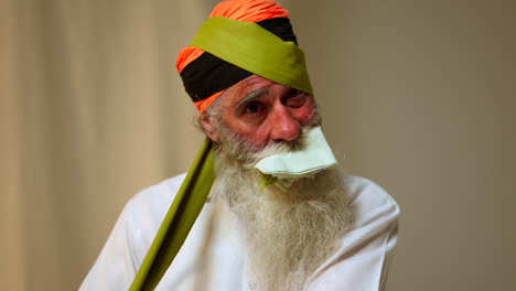 Studio-Shot-Of-Senior-Sikh-Man-With-Beard-Tying-Fabric-For-Turban-Against-Plain-Background-Shot-In-Real-Time-1